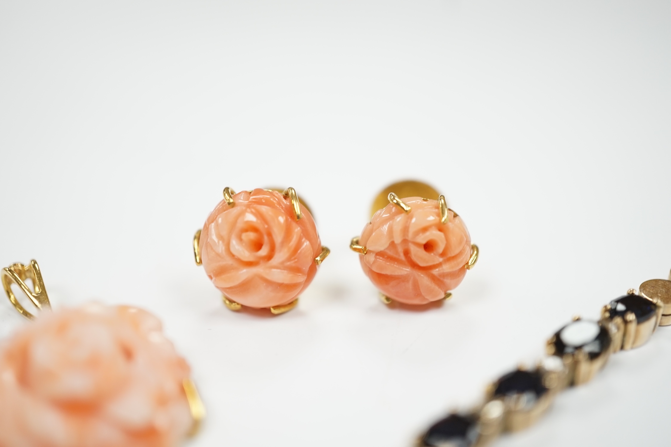 A modern 18ct and carved coral set 'rose' pendant, 16mm and a pair of matching ear studs and a yellow metal and two colour sapphire set line bracelet, 18cm.